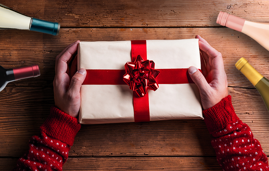 Person holding a holiday present with wine bottles surrounding it