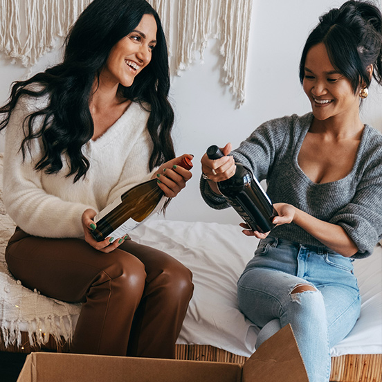 two women unboxing a shipment from One Stop Wine Shop Wine Club