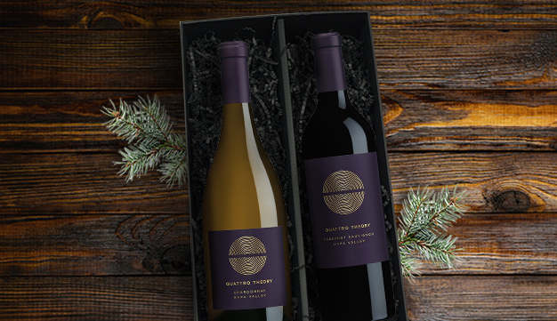Gift box of Quattro theory wines on a wooden table with fir branches