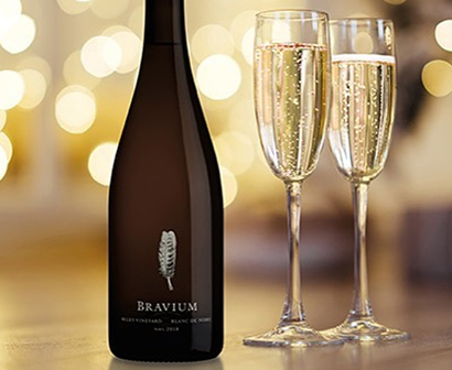 bottle and glasses of Bravium blanc de noirs with a sparkly background