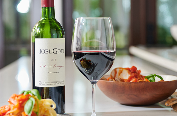 bottle and glass of Joel Gott 815 Cabernet Sauvignon next to a bowl of pasta