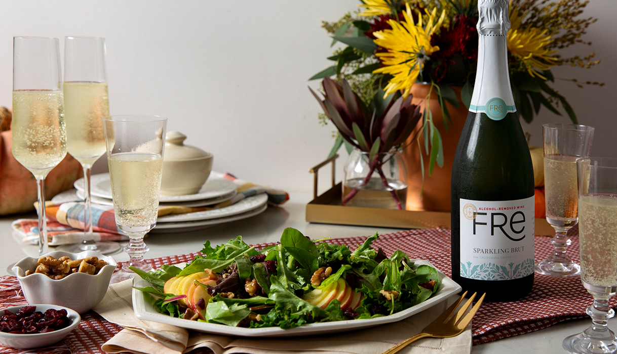 apple walnut salad next to a bottle of FRE alcohol-removed sparkling brut with festive fall flowers in the background